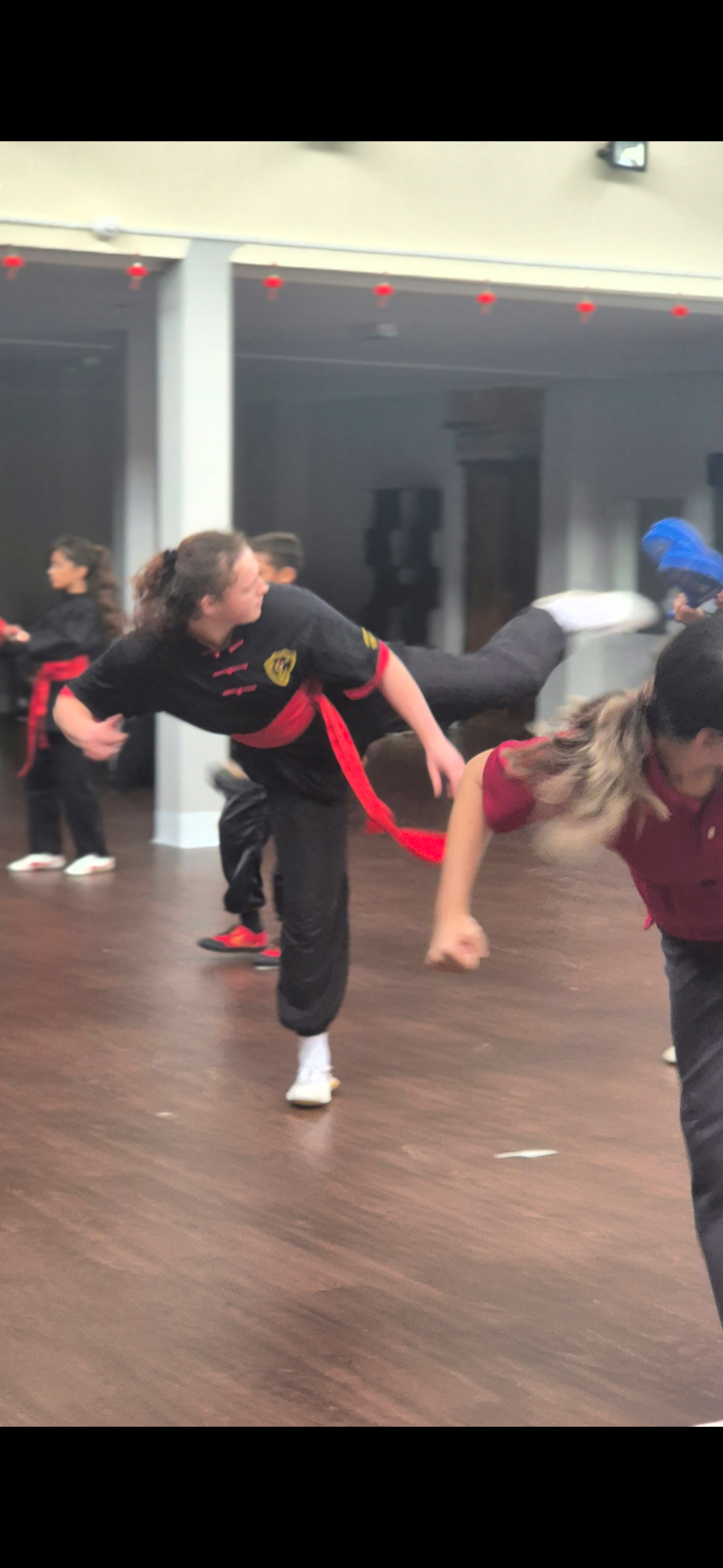 Kung Fu students practising a controlled high kick in the training hall